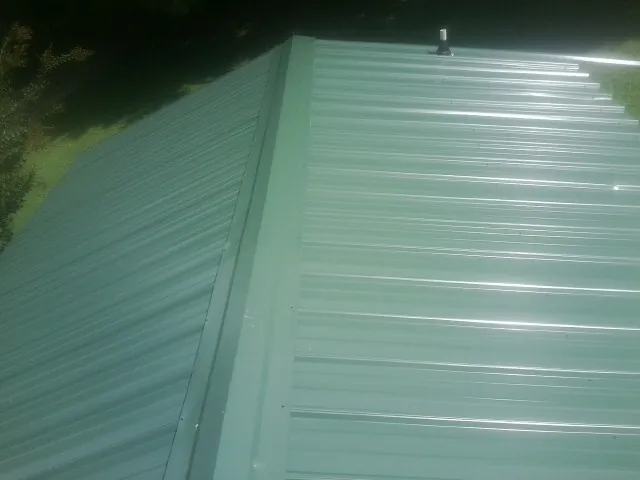 New green metal panels meeting at the ridge of a roof — Flat Roof Repair work by our crew in Tafton