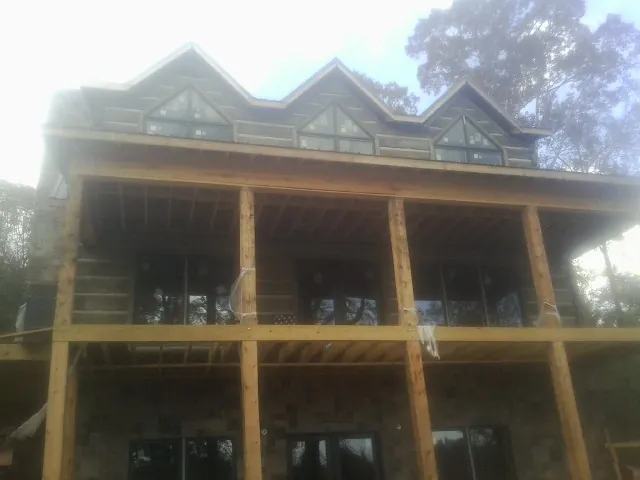 Dormers and porch framing on a large log home under construction — Roof Coating work by our crew in Tafton