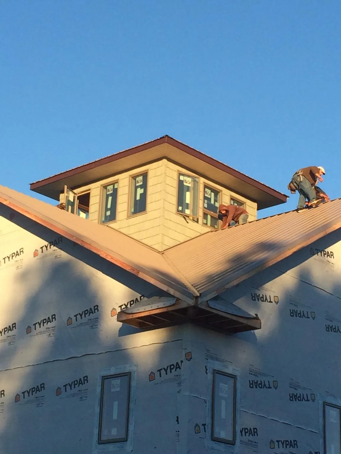 Roofers working around a rooftop cupola on a new metal roof at sunset — Roof Waterproofing in Tafton by Roofing Brothers